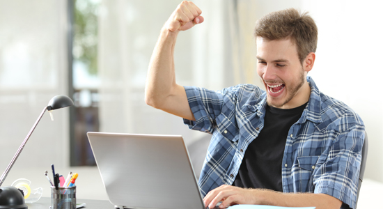 image of man using laptop and cheering